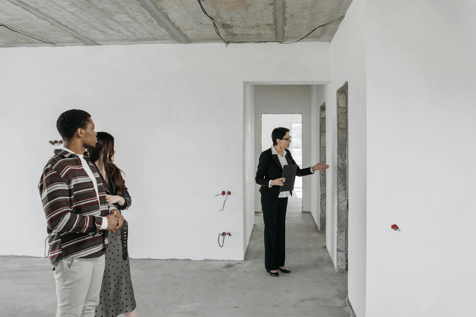 A couple explores an unfinished apartment with a real estate agent, considering property purchase options.